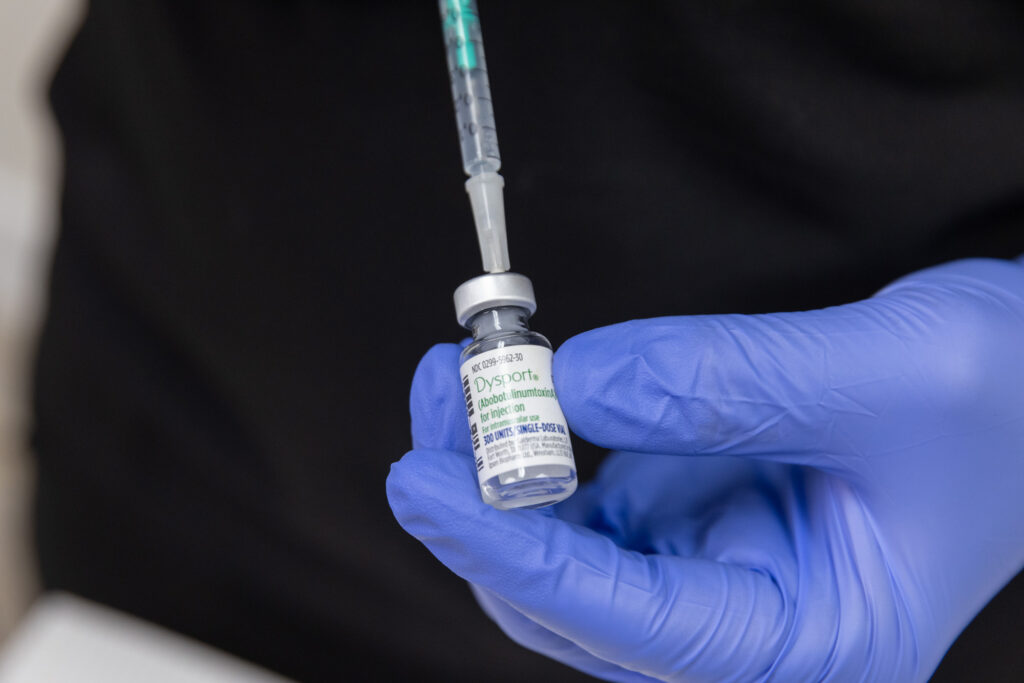 Close-up of a doctor wearing blue gloves preparing a syringe of Botox to treat a patient's bruxism in Fort Lauderdale