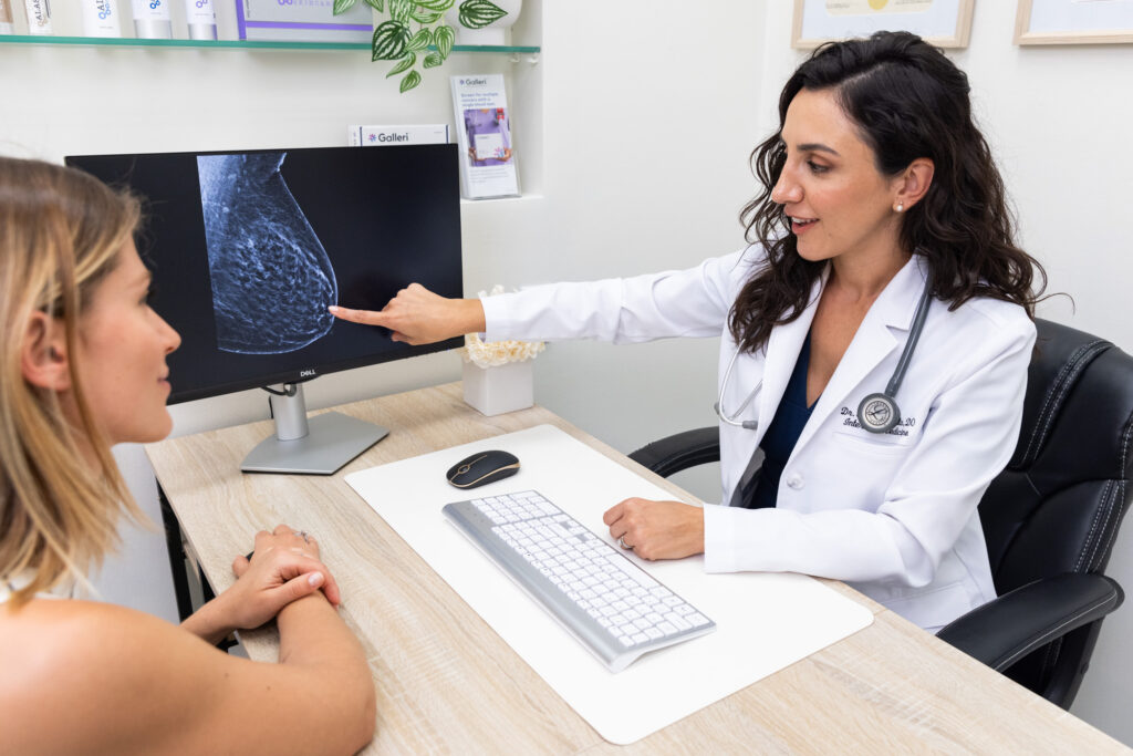 A doctor meets in-person with a female patient to discuss results on a computer for telemedicine in Fort Lauderdale