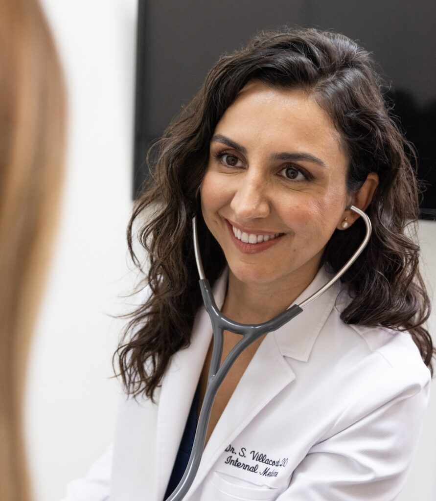 Primary care physician wearing a stethoscope and smiling at patient who is visiting her for concierge medical services in Fort Lauderdale.