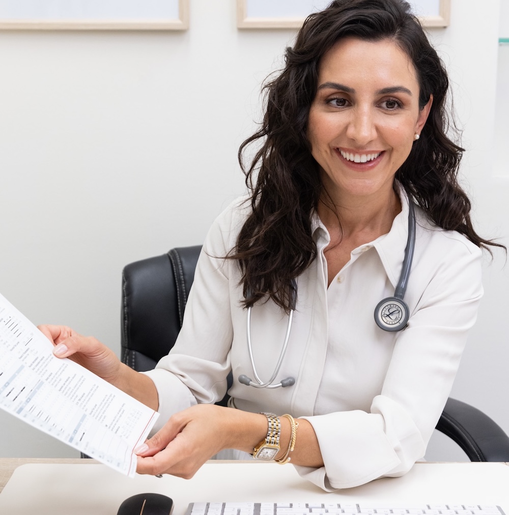 Dr. Villacorta, a concierge weight loss doctor in Fort Lauderdale, wearing a stethoscope holding InBody Body Composition test results for the patient to see.